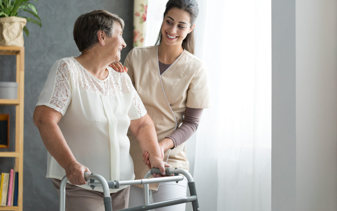 nurse helping elderly woman walk with a walker