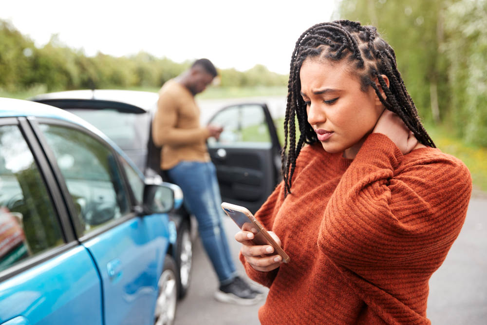 Woman standing checking phone after car accident - Lasky Justus Law - Your Savannah Law Firm for Personal Injury & Car Wrecks